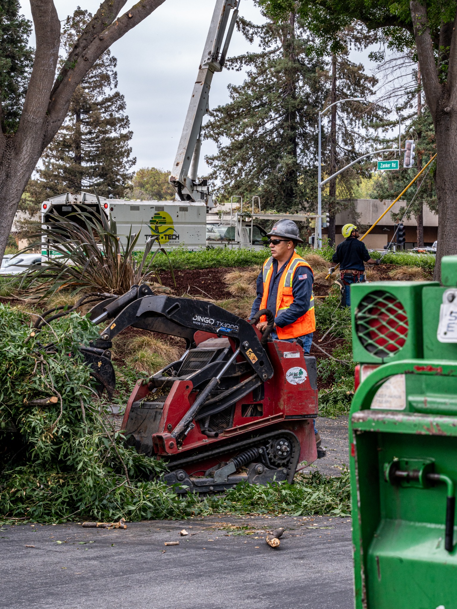 A Tree Tech crew member operating a compact loader beside the ground equipment